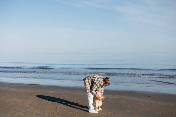 Father and toddler daughter standing on beach near adriatic sea in Italy 