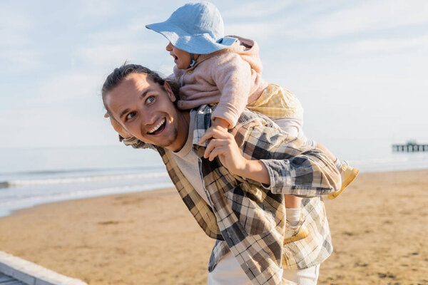 Young father having fun with daughter in panama hat on beach in Treviso 