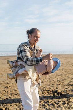 Mutlu genç baba Treviso sahilinde bebekle oynuyor.