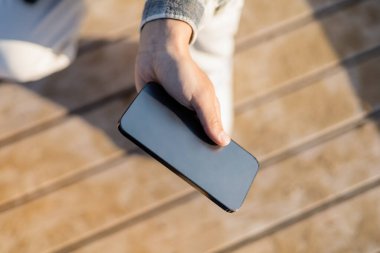 Akıllı telefonu boş ekran ile tutan adamın kırpılmış görüntüsü 
