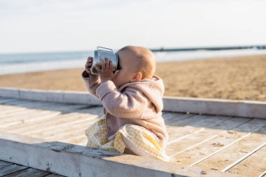 İtalya 'da sahilde fincandan içen küçük kız. 
