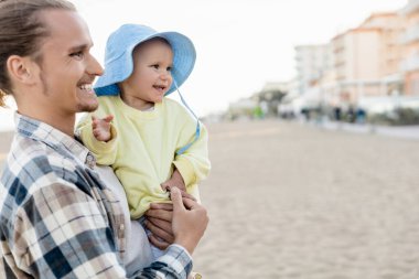 Gülümseyen baba ve bebek İtalya 'da sahile bakıyor. 