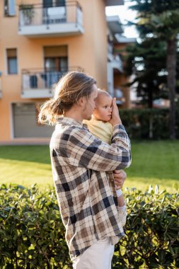 Father in shirt touching baby girl on urban street in Treviso clipart