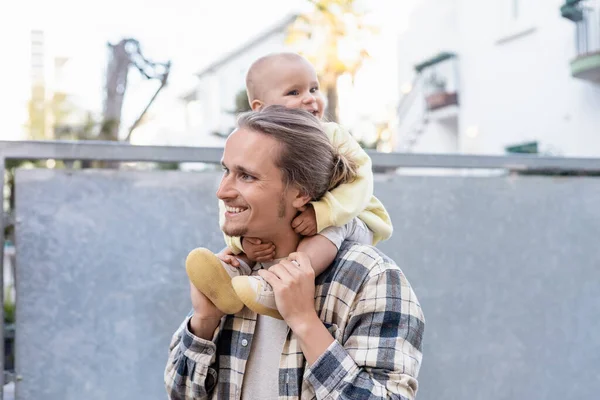 stock image Smiling baby sitting on shoulders of young father on urban street in Treviso