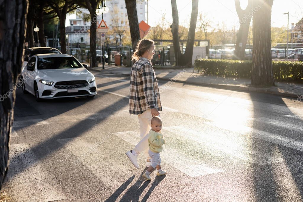 Father and toddler girl walking on crosswalk on urban street in Treviso