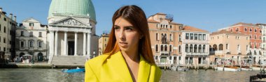 redhead woman in yellow clothes looking away near venetian cityscape on background, banner clipart