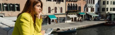 Sarı ceketli kızıl saçlı kadın Venedik 'te rüya görürken gözlerini kaçırıyor.