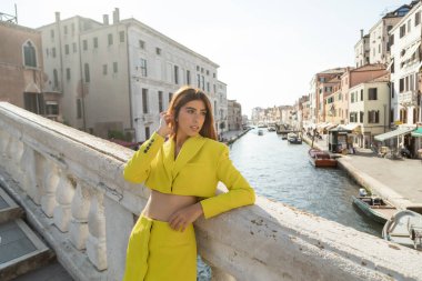 Sarı elbiseli genç bir kadın Venedik 'teki Büyük Kanal üzerindeki köprüde kızıl saç düzeltiyor.