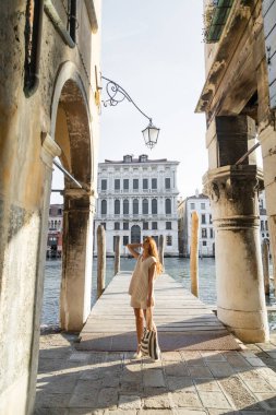 Venedik 'teki Büyük Kanal ve antik binaların yanında çizgili çantalı bir kadın.