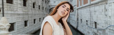 young woman looking at camera near medieval venetian building on blurred background, banner clipart