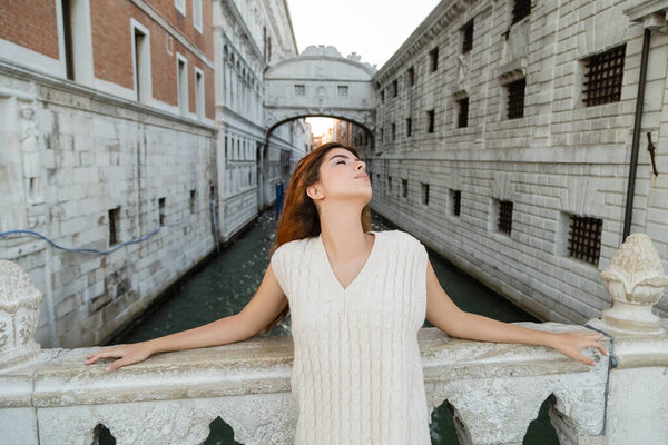 young woman with closed eyes near Sighs Bridge and medieval prison in Venice