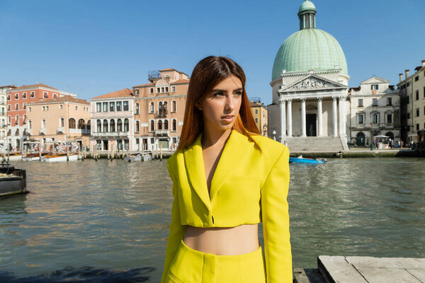 redhead woman in yellow crop jacket looking away near Grand Canal in Venice