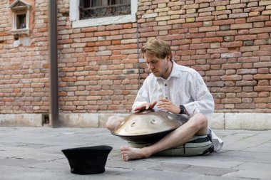 Musician playing handpan on urban street in Venice  clipart