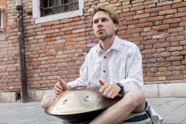 Street musician holding handpan outdoors in Venice 