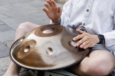 Cropped view of street musician performing hang drum on urban street 