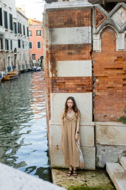 Venedik 'teki eski binanın yakınındaki kameraya bakan genç bir kadın. 