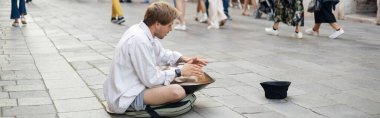 VENICE, ITALY - MAY 22, 2022: Side view of street musician playing hang drum outdoors, banner 