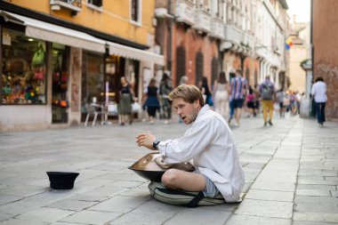 VENICE, ITALY - MAY 22, 2022: Street musician performing hand drum on urban street 