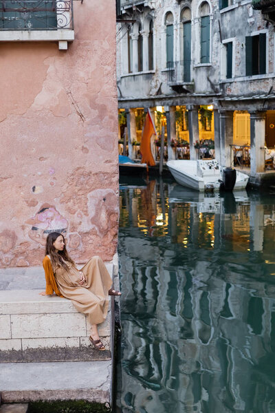 Side view of young pregnant woman sitting on stairs of building in Venice 
