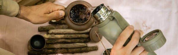 Top view of man pouring hot water in teapot outdoors, banner 