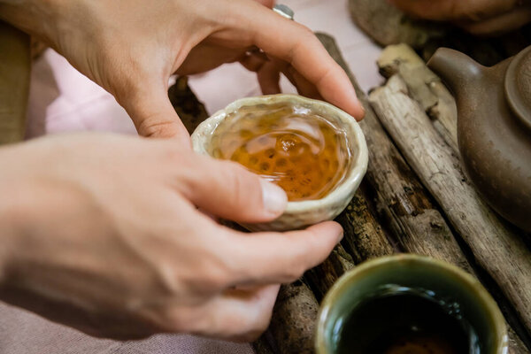 Cropped view of woman holding bowl near wooden board during tea ceremony outdoors 