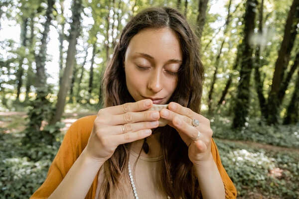 Brunette woman holding tea bowl in forest 