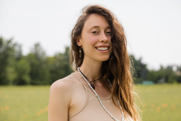 Портрет улыбающейся брюнетки, улыбающейся в поле на камеру 