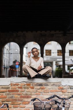 Treviso 'daki şehir sokağında elinde kalem ve defter tutan Afro-Amerikan turist.