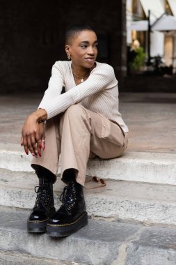 Genç Afrikalı Amerikalı kadın İtalya 'da merdivenlerde otururken gözlerini kaçırıyor.