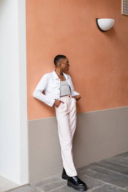 Kısa saçlı afro-amerikalı turistin binanın yakınına bakmamasının yan görüntüsü 