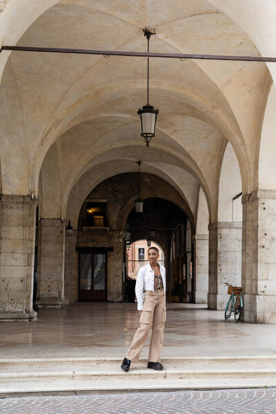 Smiling african american woman posing near old building on urban street in Treviso