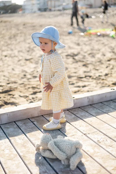 Baby girl in panama hat standing near toy on pier in Treviso — Stock Photo