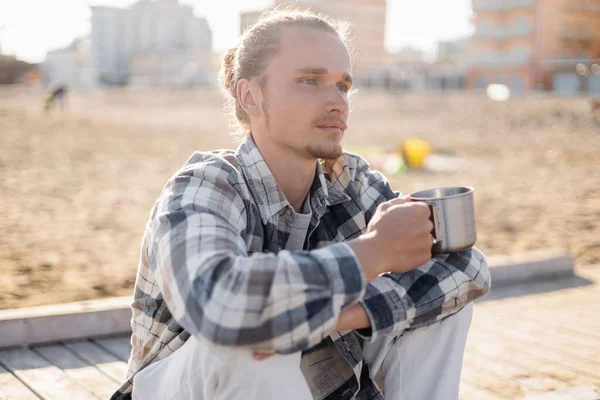 Молодий чоловік тримає чашку і дивиться на пляж в Італії. — стокове фото