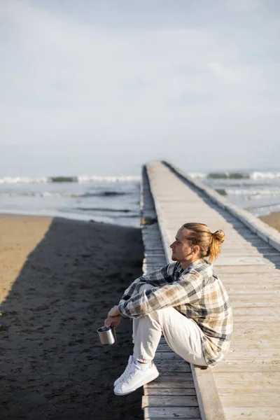 Vista lateral del hombre sosteniendo la taza en el muelle cerca del mar adriático en Italia - foto de stock