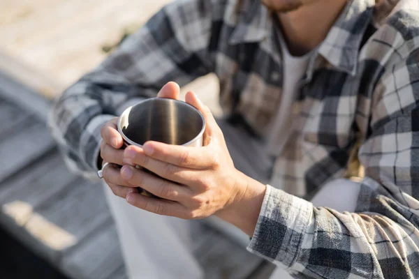 Verschwommene Sicht auf verschwommenen Mann mit Becher auf Holzpier — Stockfoto