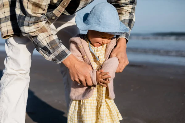 Dad holding cheerful baby daughter on beach — Stock Photo