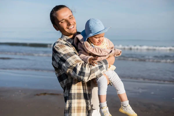 Buon papà che tiene la bambina vicino al mare adriatico sfocato in Italia — Foto stock