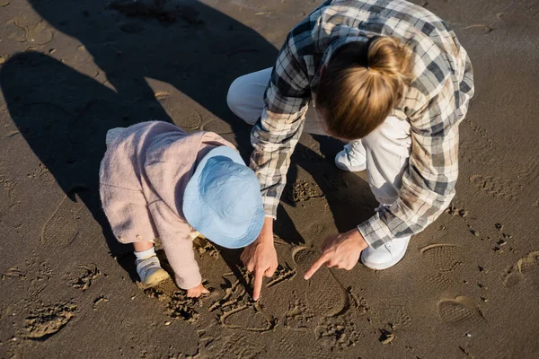 Overhead view of man and baby girl drawing on beach — Stock Photo