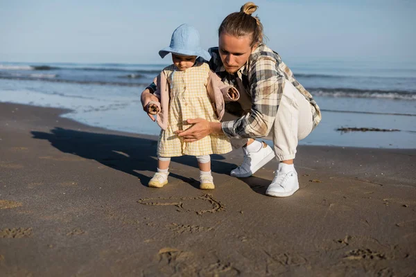 Parent et enfant regardant signe du cœur sur la plage de Trévise — Photo de stock