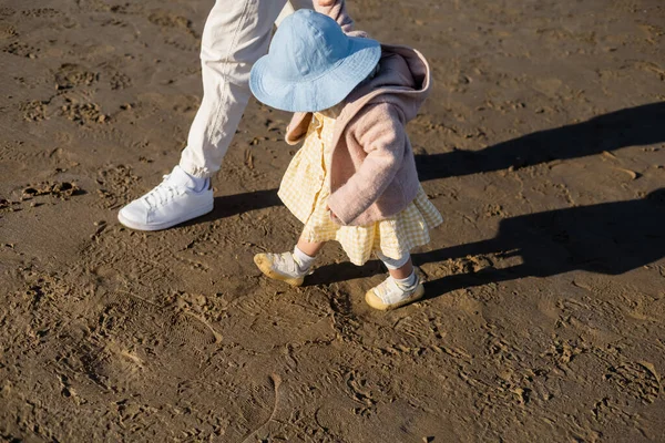 Высокий угол обзора маленькой девочки в панамской шляпе, идущей рядом с папой на пляже — стоковое фото