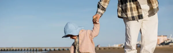 Отец держит за руку маленькую дочь на пляже в Тревизо, баннер — стоковое фото
