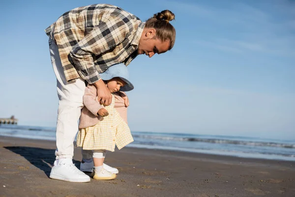 Jeune homme vêtu d'une veste sur bébé fille sur la plage près de la mer adriatique en Italie — Photo de stock