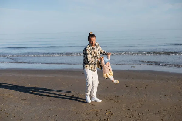Довговолосий батько бавився з донечкою на пляжі біля моря атріатичного моря в Італії. — стокове фото