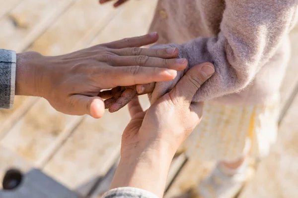 Vista recortada de papá cogido de la mano en la arena de hija en la playa - foto de stock