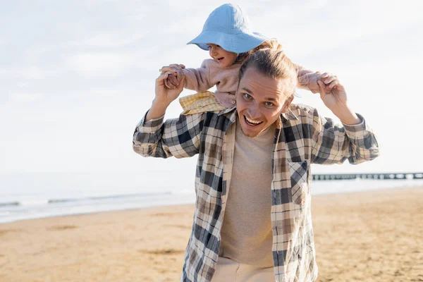 Bebé alegre cogido de la mano del padre en la playa en Italia - foto de stock