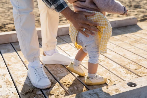 Cropped view of man touching baby daughter on wooden pier — Stock Photo