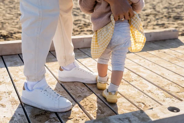 Обрезанный вид отца, регулирующего штаны маленькой девочки на пирсе — стоковое фото