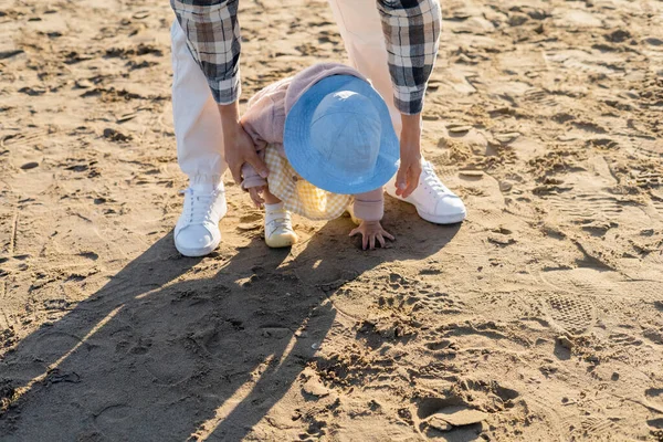 Мужчина поддерживает маленькую дочь на песчаном пляже — стоковое фото