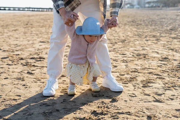 Родители держатся за руки ребенка в панамской шляпе на пляже — стоковое фото