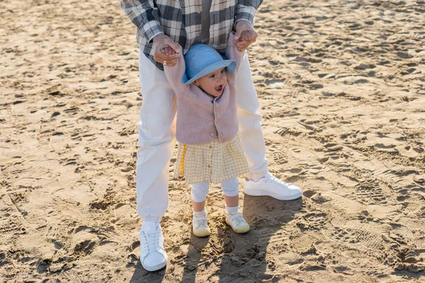 Homem de mãos dadas de bebê alegre no chapéu de panamá na praia — Fotografia de Stock